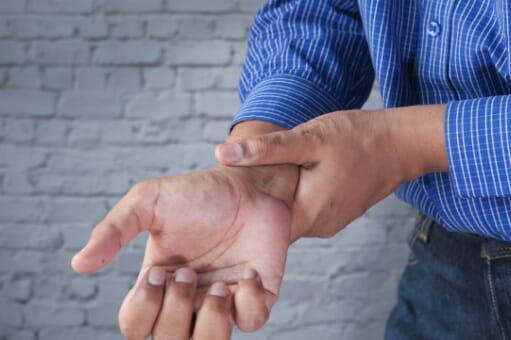 man in office holding his arthritic wrist